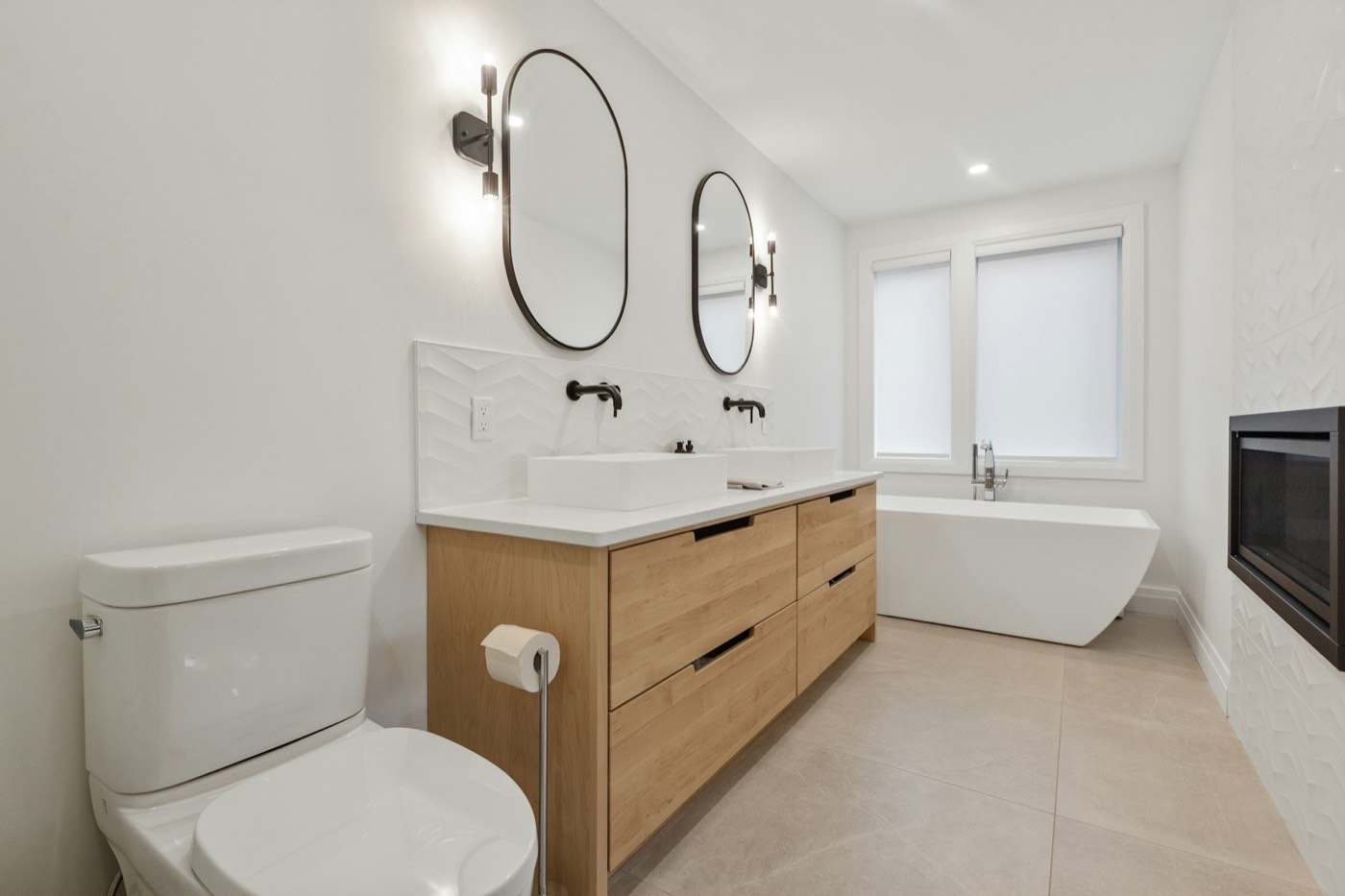 A finished bathroom with a timber vanity, matte black tapware and a freestanding bath.