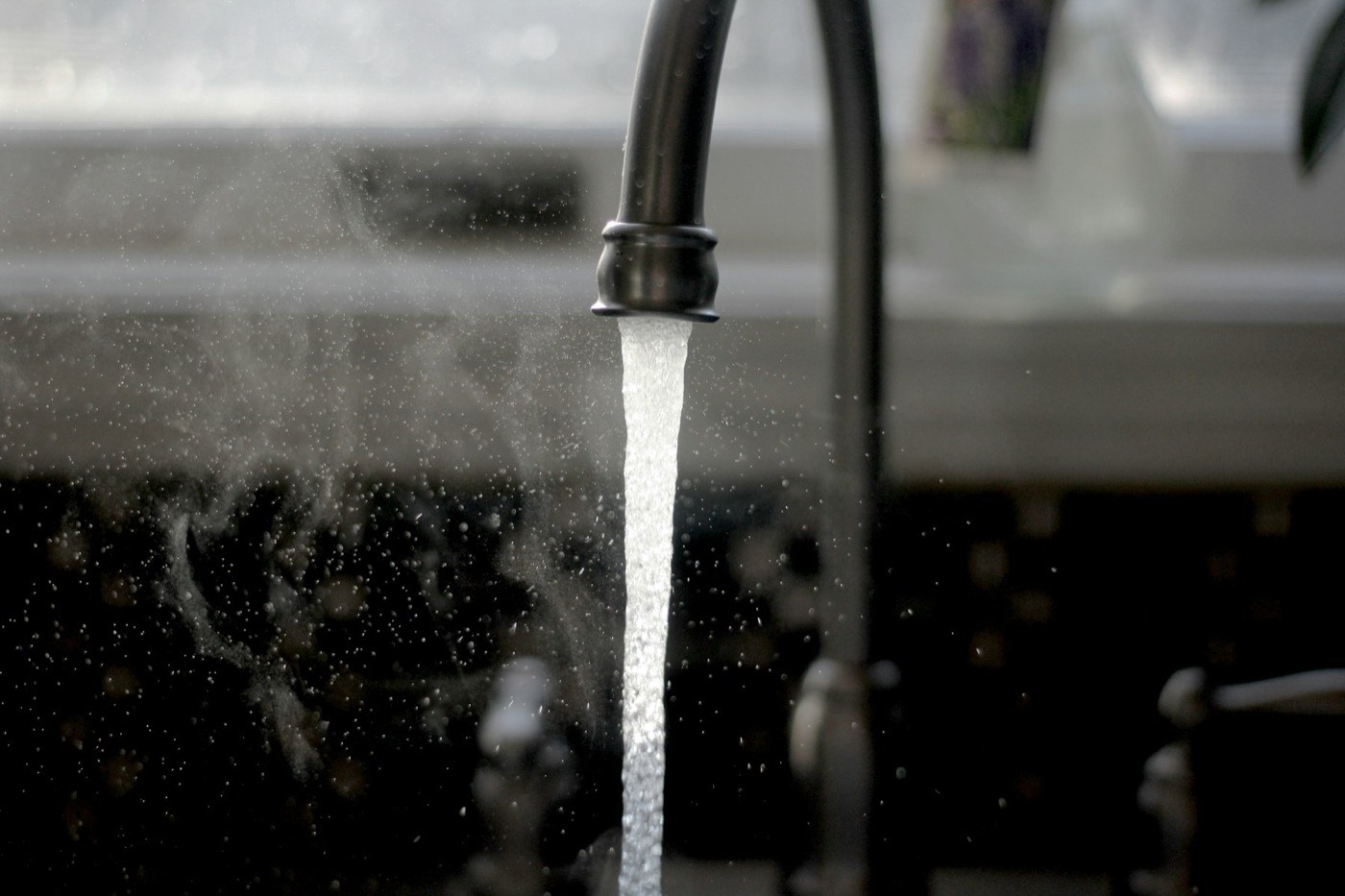 Steaming hot water running from a kitchen tap.